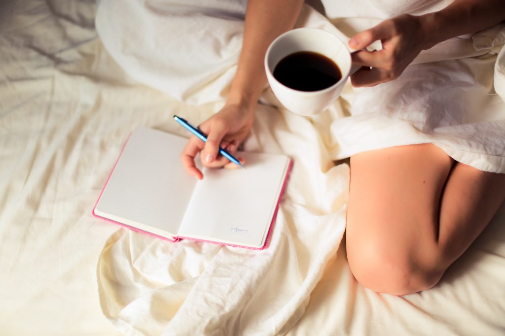 Woman journalling on bed. 