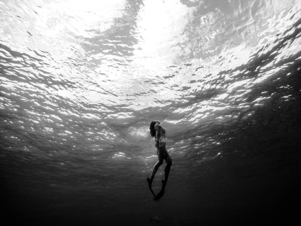 Free diver uses breath hold to float under the surface. 