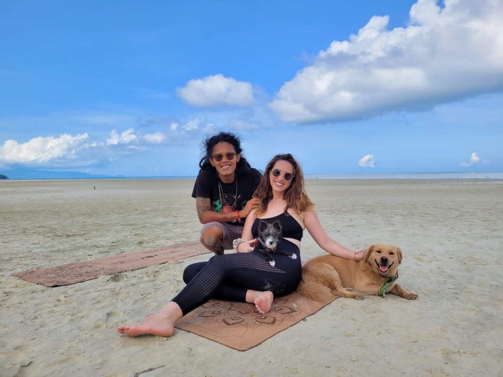 Roz and Chris on the beach in Koh Phangan with their two dogs and cork yoga mats from Studio Layla.